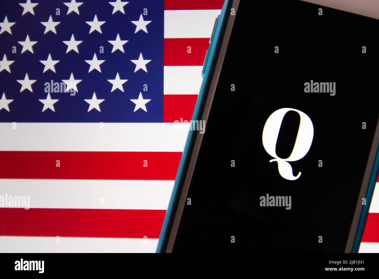 Kumamoto, JAPON - octobre 20 2020 : logo Qanon sur iPhone avec arrière-plan drapeau américain. Qanon est un groupe de conspiration d'extrême-droite Banque D'Images