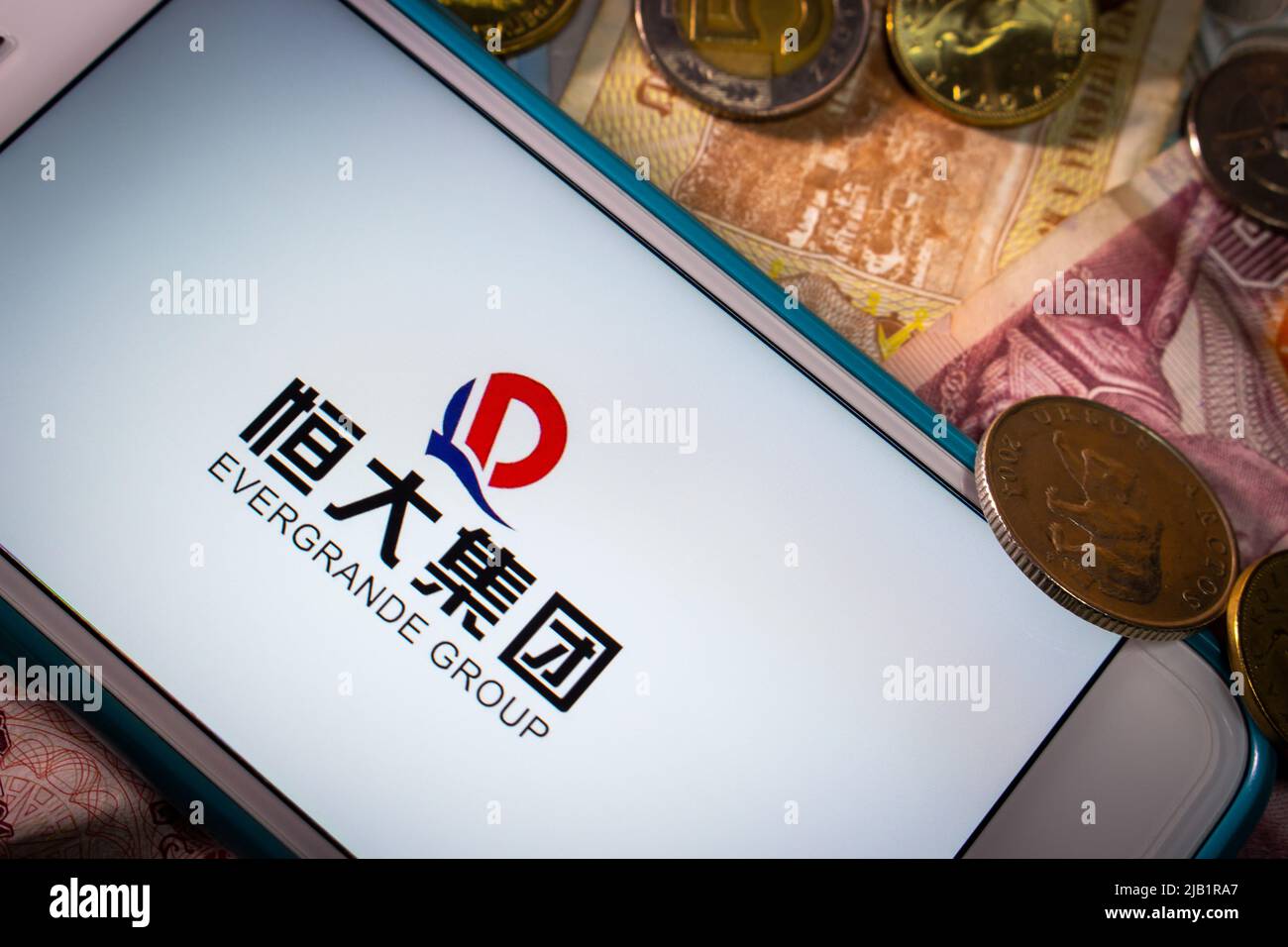 Kumamoto, JAPON - septembre 23 2021 : le Groupe Evergrande, le plus grand promoteur immobilier de Chine, sur iPhone avec pièces et billets de banque aléatoires Banque D'Images