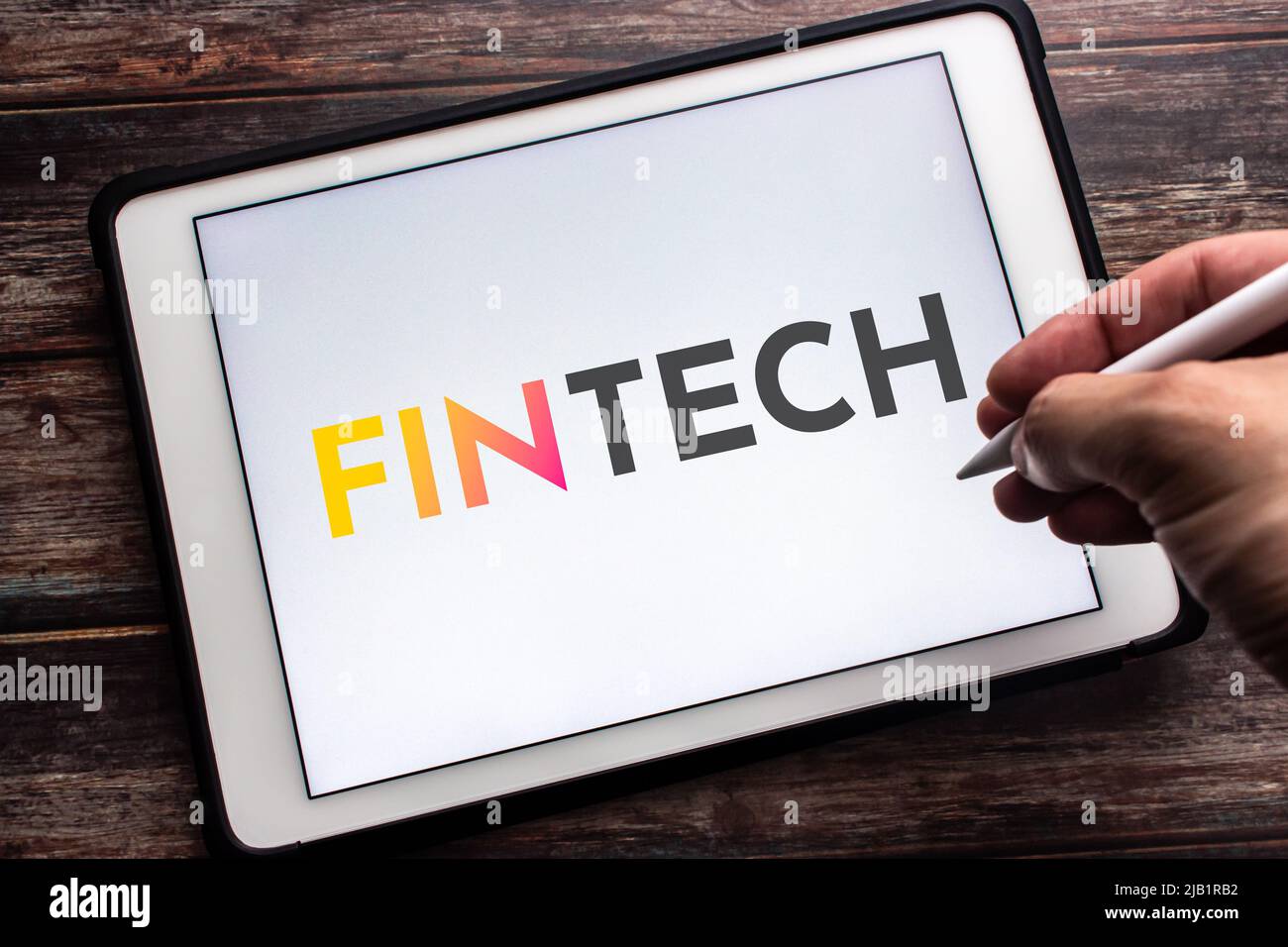 Gros plan sur le mot-clé FinTech (technologie financière) sur la tablette. Le concept de la technologie et des méthodes financières. Main tenant le stylet sans fil Banque D'Images