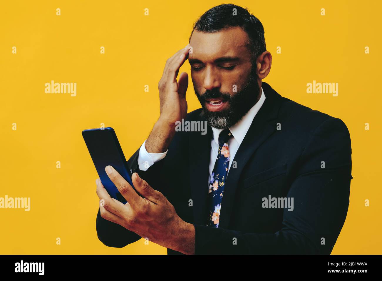 portrait d'un homme barbu inquiet et inquiet en costume et cravate avec un smartphone appel vidéo main sur le temple fermé yeux studio Banque D'Images