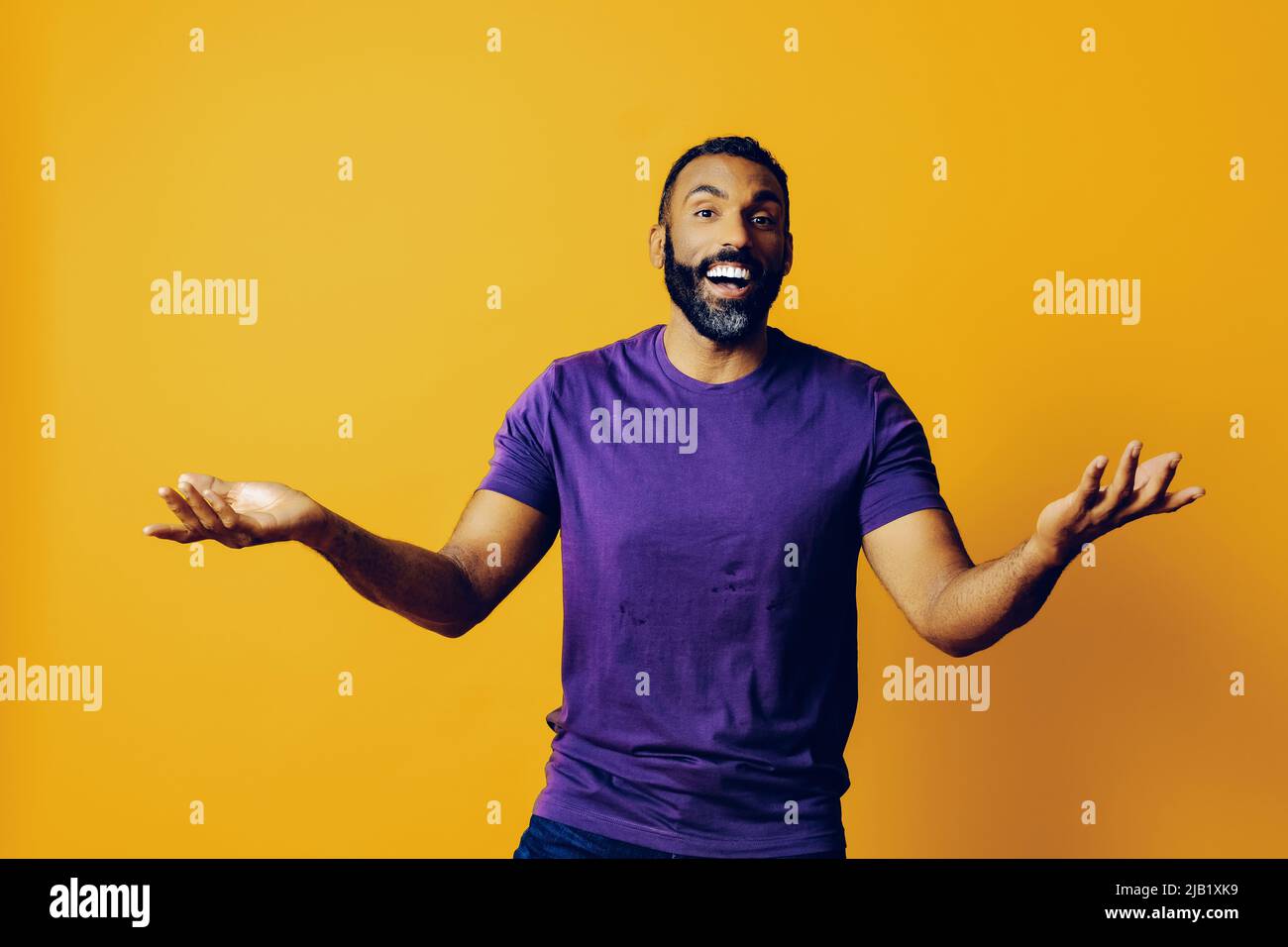 portrait d'un homme gagnant réussi avec une barbe et un t-shirt violet célébrant avec bras vers le haut sur fond jaune studio Banque D'Images