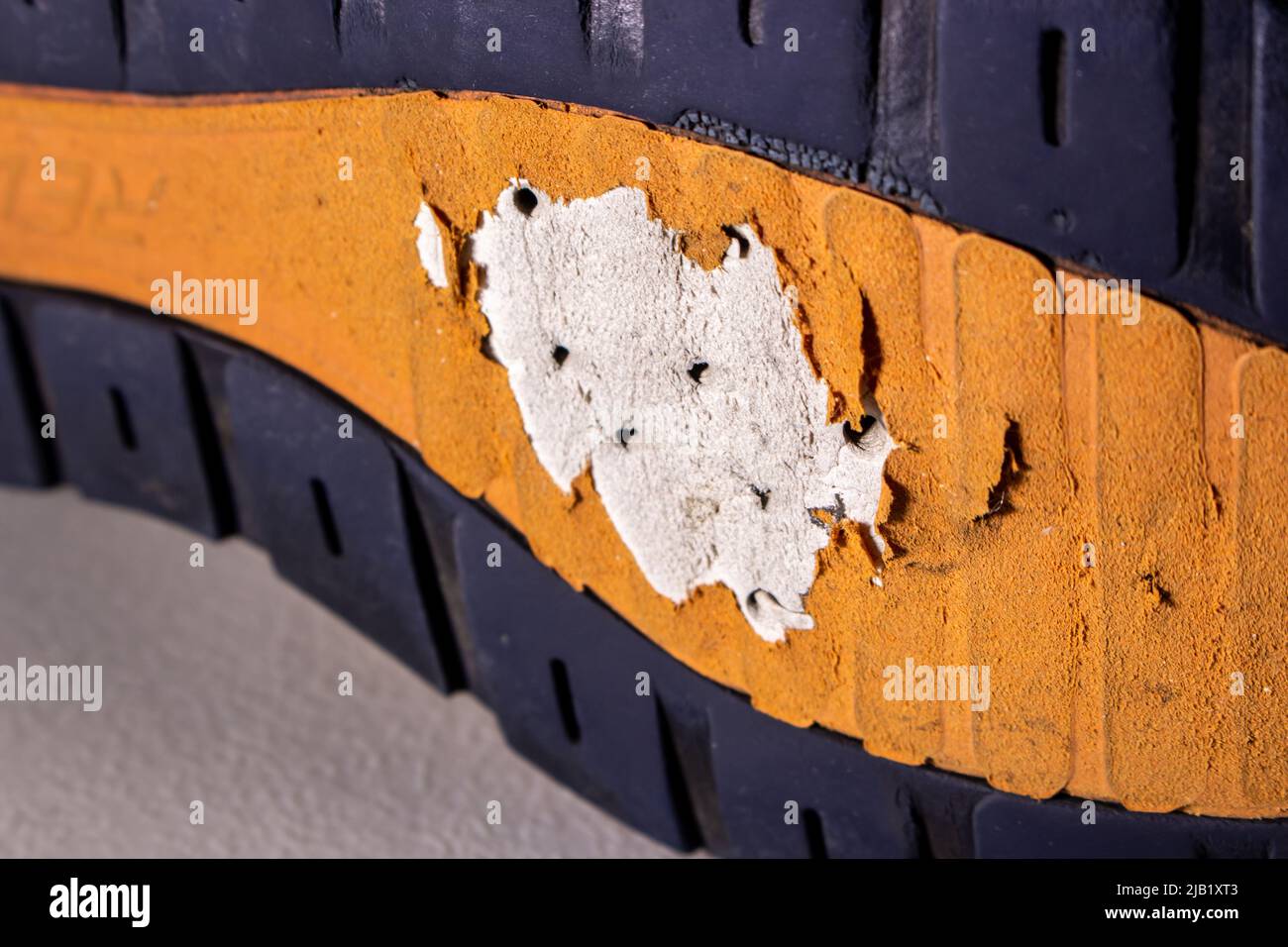 Gros plan sur l'ancienne semelle de chaussure cassée. La semelle des chaussures en image est très usée et présente des trous. Banque D'Images