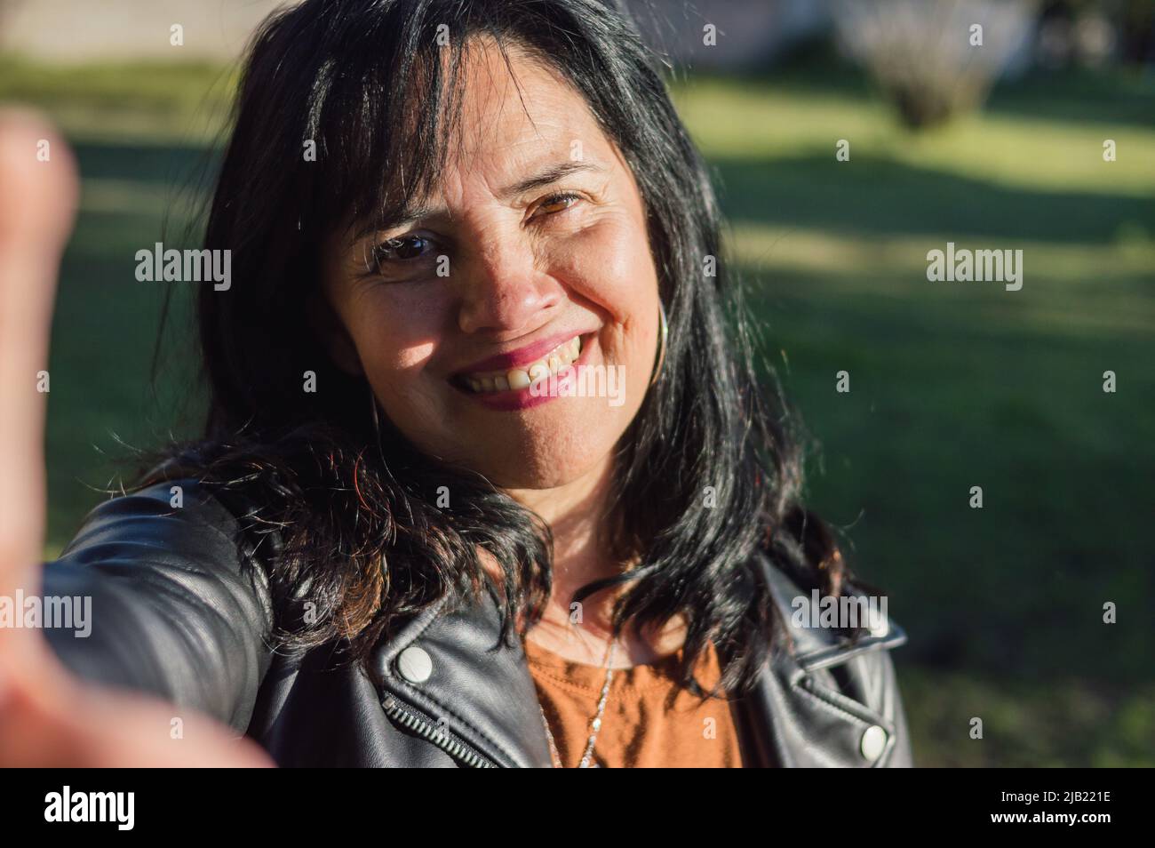 latino-caucasien femme adulte, à l'extérieur dans la ferme arrière-cour souriant prenant un selfie, téléphone caméra perspective. technologie et concept de communication. Banque D'Images