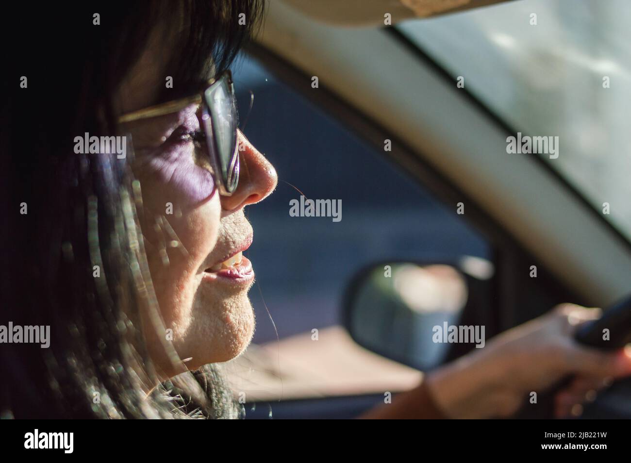 gros plan à l'intérieur de la voiture d'une femme adulte caucasienne avec des lunettes de soleil en voiture, perspective du passager avant. Banque D'Images