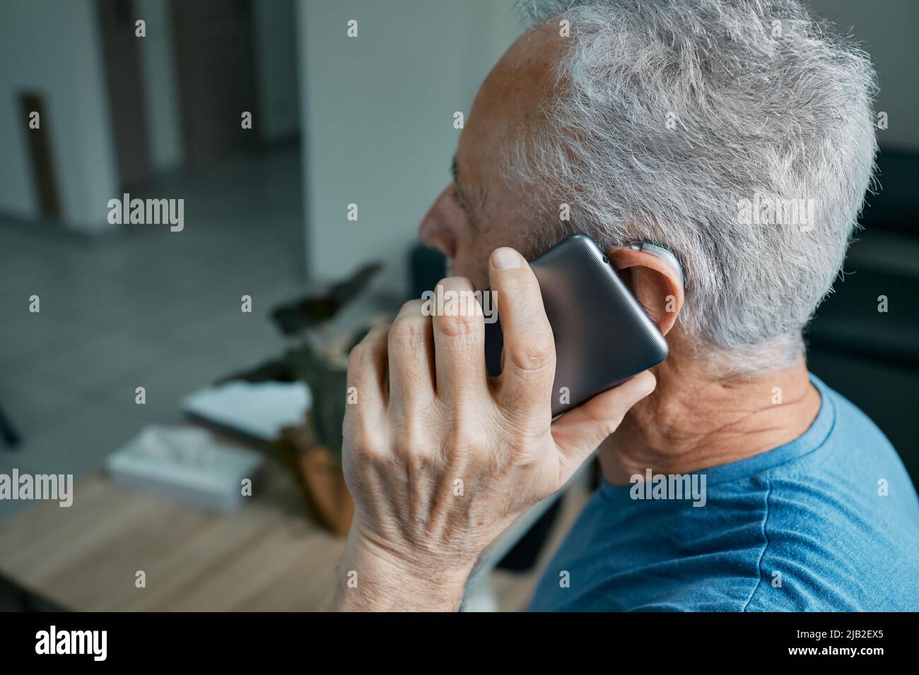 L'homme âgé avec une prothèse auditive a une vie entière et peut entendre son interlocuteur au téléphone. Solution auditive et technologie innovante Banque D'Images