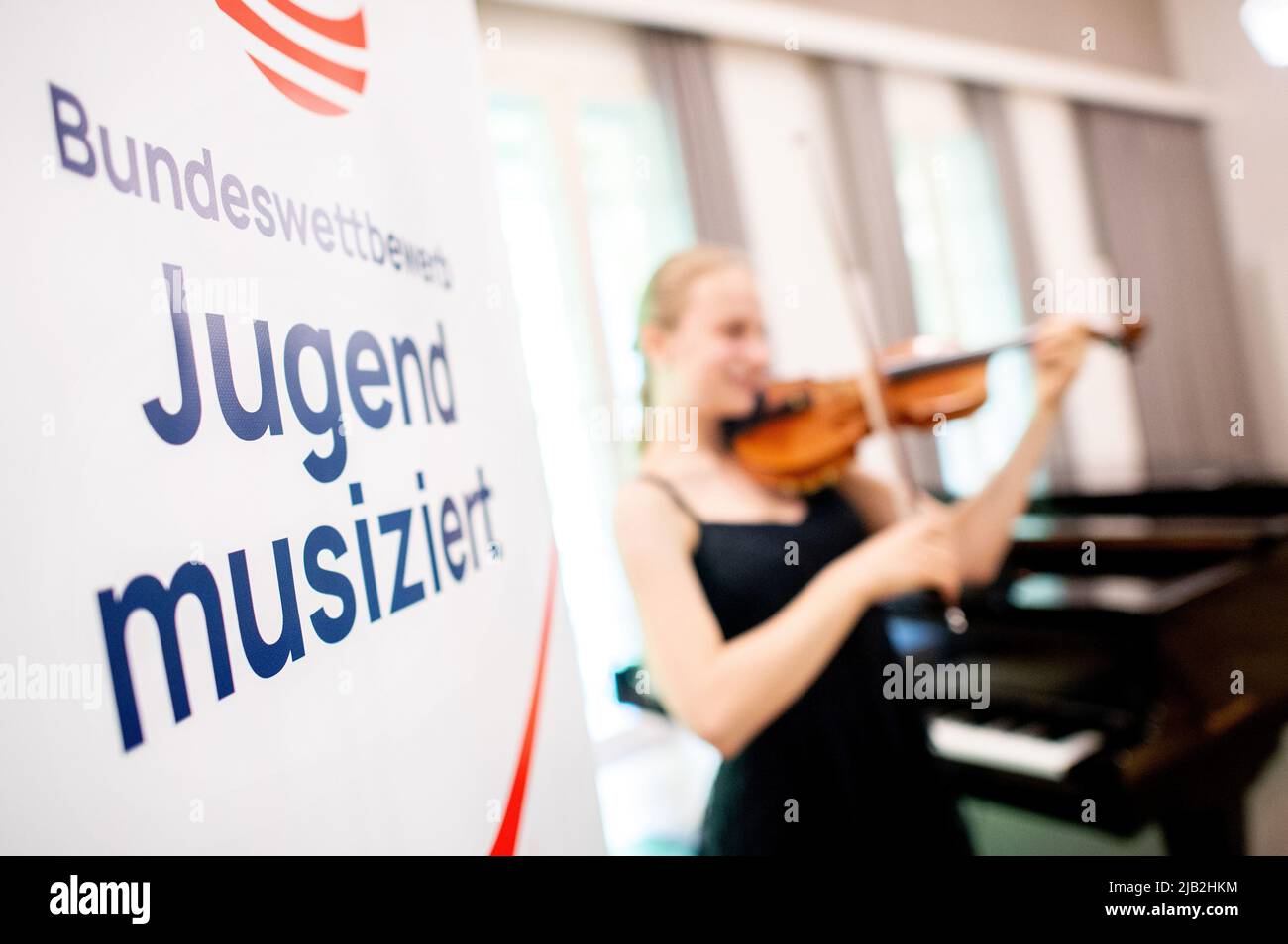 Oldenburg, Allemagne. 02nd juin 2022. Les mots «Bundeswettbewerb Jugend musiziert» sont écrits sur une affiche de l'ancien Parlement tandis qu'une fille joue son violon. Environ 2300 jeunes musiciens participent à la compétition nationale, qui se tient en direct et devant un public pour la première fois en deux ans. Credit: Hauke-Christian Dittrich/dpa/Alay Live News Banque D'Images