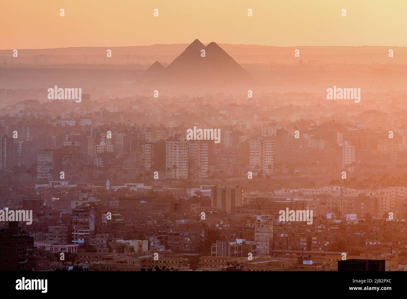Égypte, le Caire. Vue d'ensemble du Caire au coucher du soleil avec l'une des pyramides de Gizeh à l'arrière. Banque D'Images