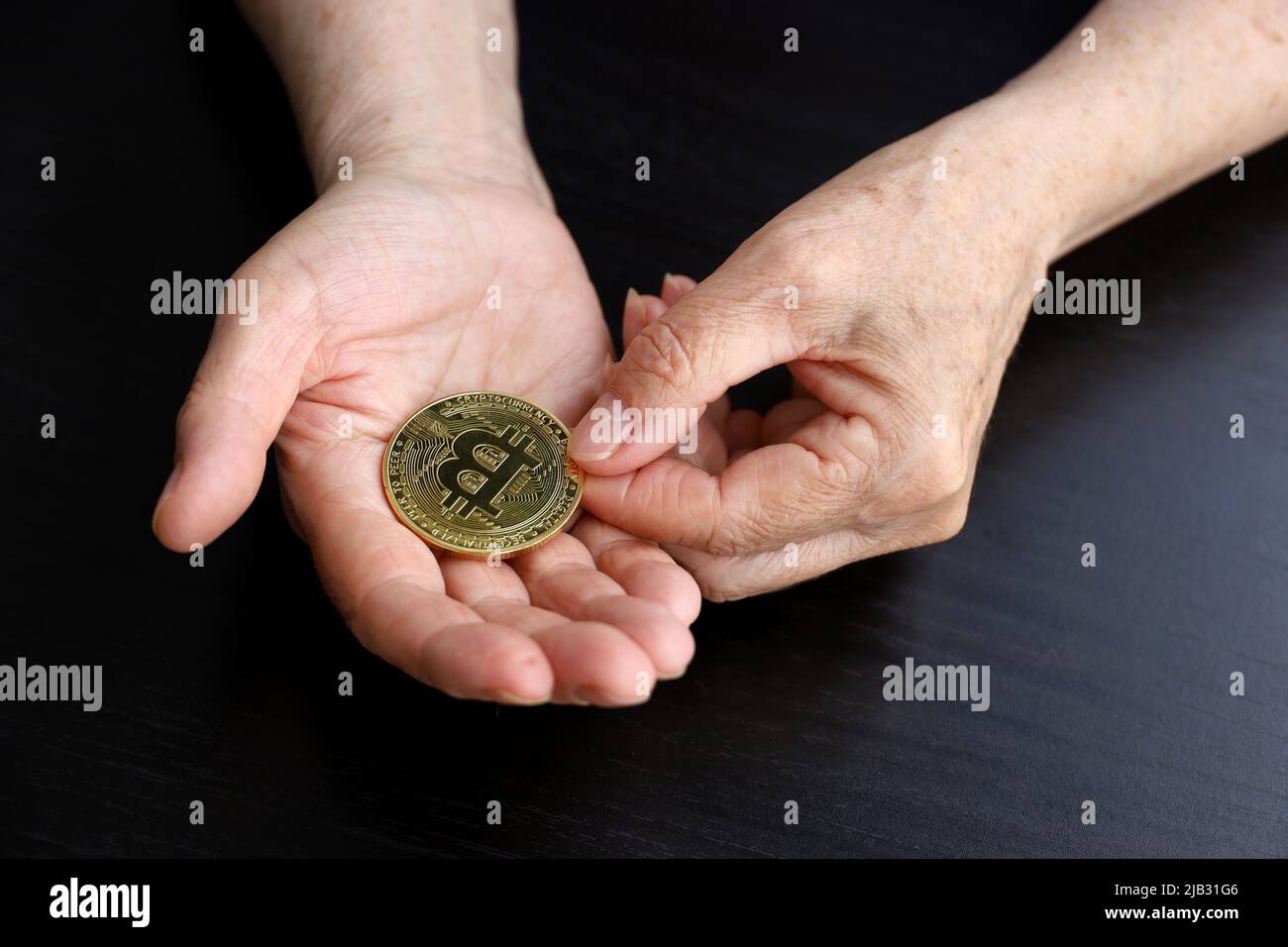 Bitcoin dans les mains froissées de femme âgée, concept de l'épargne-retraite. Monnaie électronique décentralisée, crypto-monnaie Banque D'Images