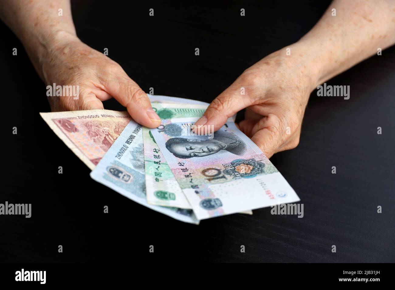 Femme âgée avec des billets de banque en yuan dans les mains froissées. Concept des paiements de pension en Chine, épargne à la retraite, retraité chinois avec de l'argent Banque D'Images