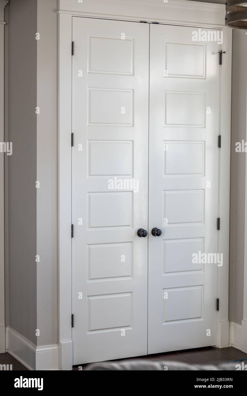 Une paire ou un ensemble de deux placard d'entrée de hall peint en blanc a fermé cinq portes de panneau dans une nouvelle maison de construction avec des murs grèges Banque D'Images
