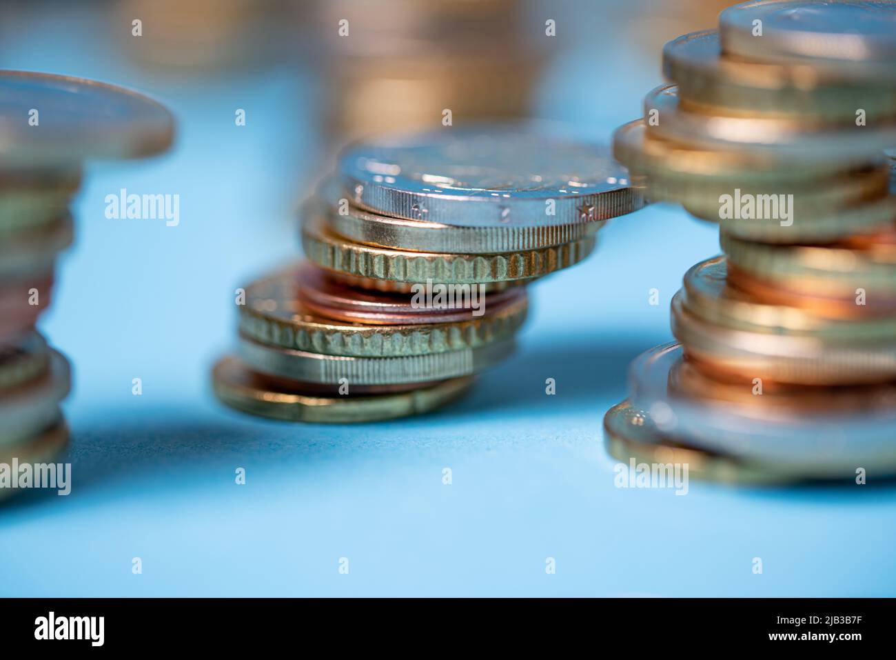Pièces de monnaie empilées sur fond bleu. Pièces en euros de l'Union européenne. Les devises et les espèces s'empilent dans les tours Banque D'Images