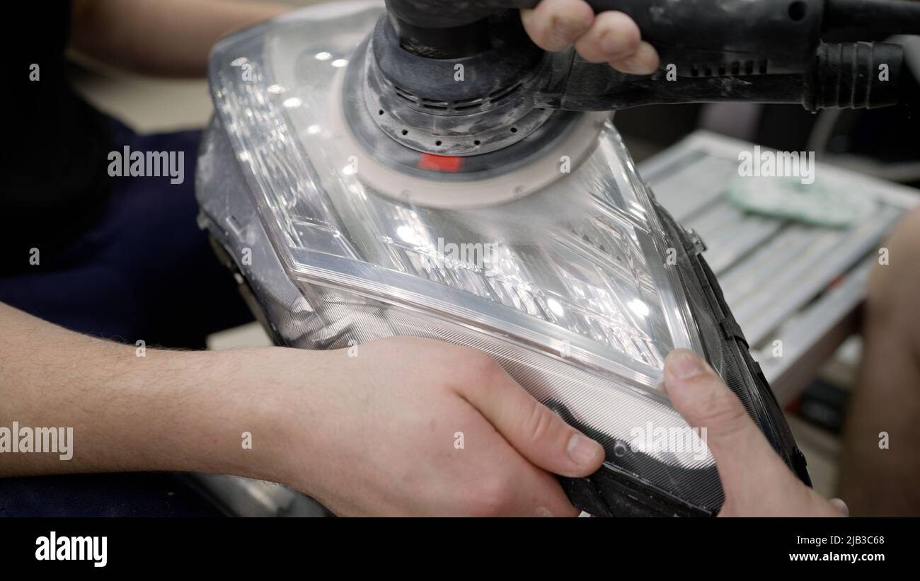 Le processus de polissage des phares d'une voiture chère. Le maître polit le phare de la voiture à l'aide d'une machine à écrire. Maître méchan Banque D'Images