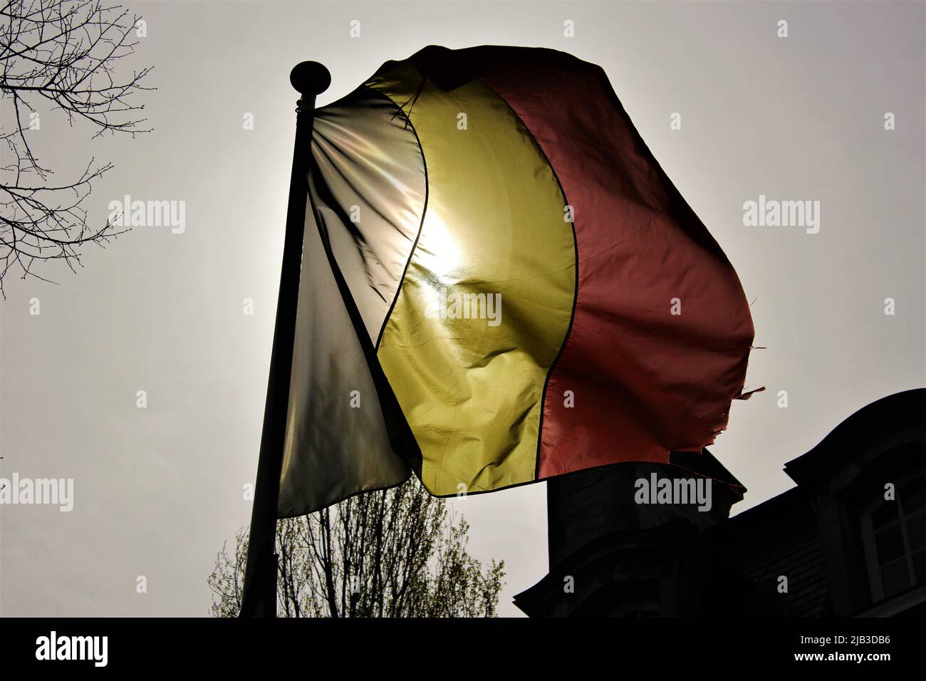 Drapeau belge rétroéclairé par le soleil volant dans le vent Banque D'Images