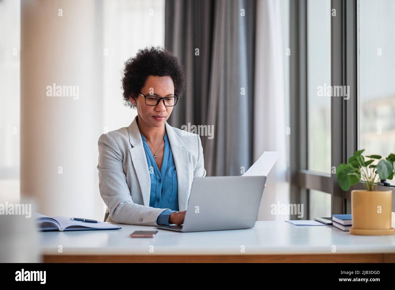 Femme d'affaires ciblée utilisant un ordinateur portable. Une femme de direction analyse le document lorsqu'elle est assise à son bureau. Elle travaille au siège social. Banque D'Images
