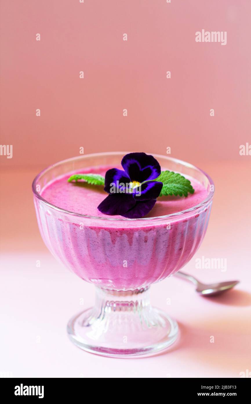 Mousse de cassis aux baies garnie de fleurs de alto et de feuilles de baume de citron. Banque D'Images