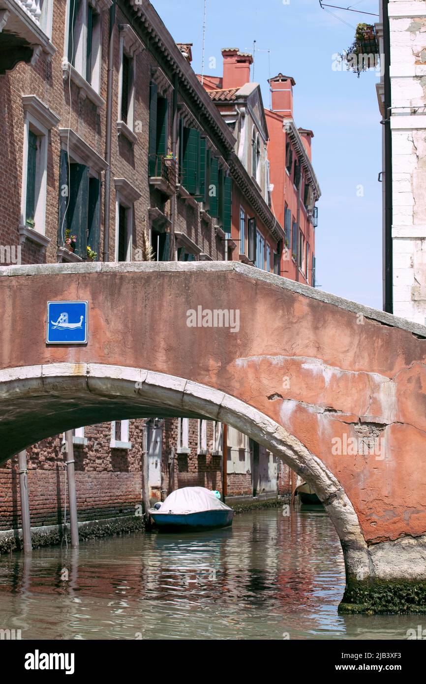 Vue romantique sur l'étroite rue de Venise avec de vieux bâtiments et un pont au-dessus d'un canal. Bateau flottant sur l'eau, ciel bleu jour ensoleillé. Vacances italiennes. Banque D'Images