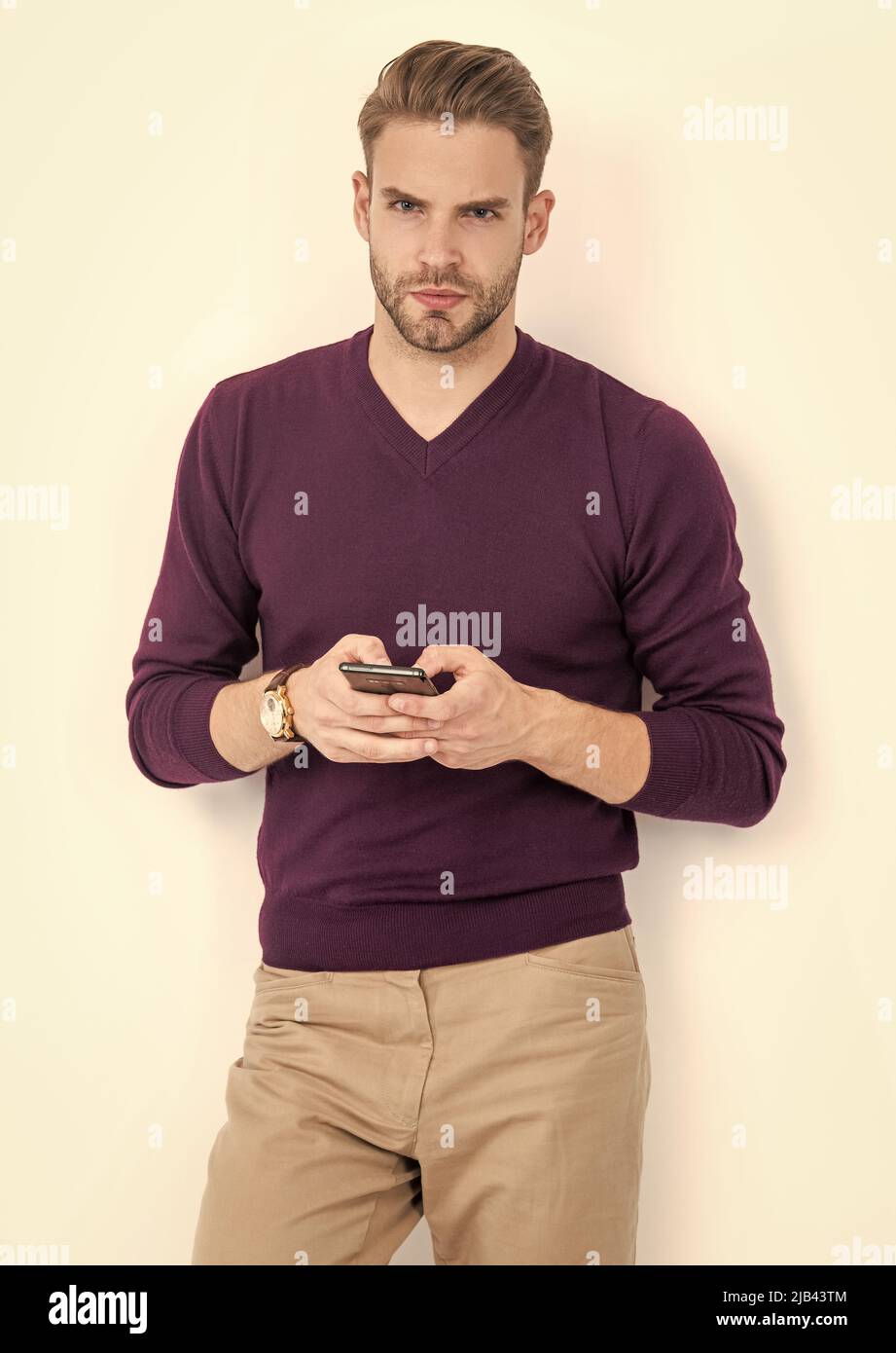Beau homme dans un style décontracté SMS sur téléphone portable isolé sur blanc, sms Banque D'Images