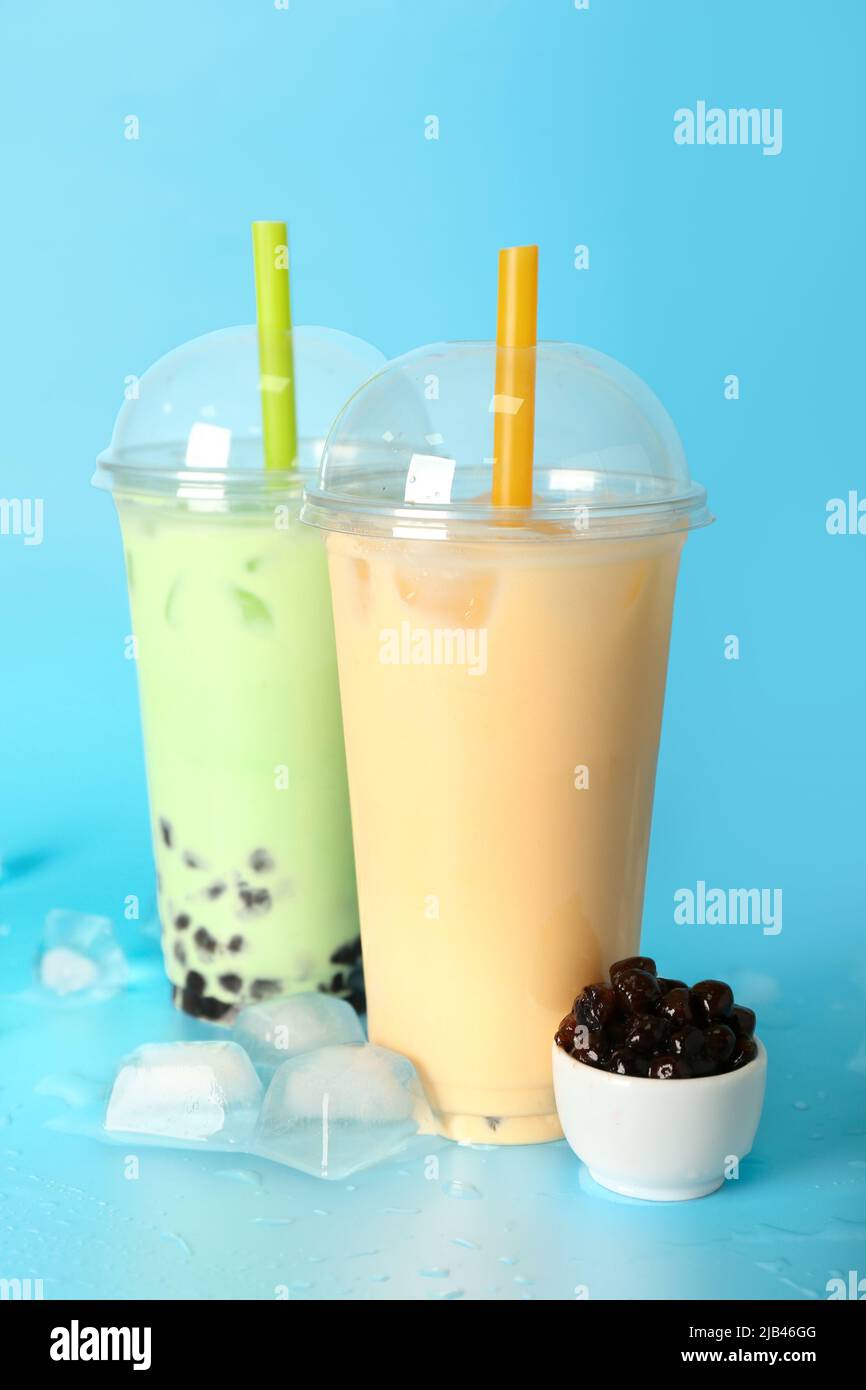 Tasses en plastique de délicieux thé moussant avec baies et glaçons sur fond bleu Banque D'Images