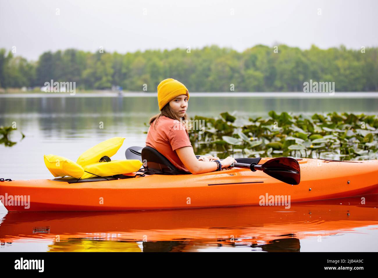 Jeune fille attrayante assise dans l'eau encore de canoë avec gilet de vie Banque D'Images