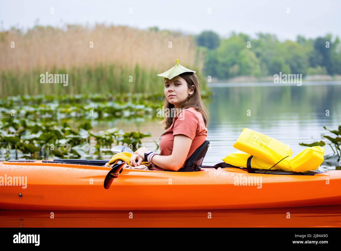 Jeune fille attrayante assise dans l'eau encore de canoë avec gilet de vie Banque D'Images