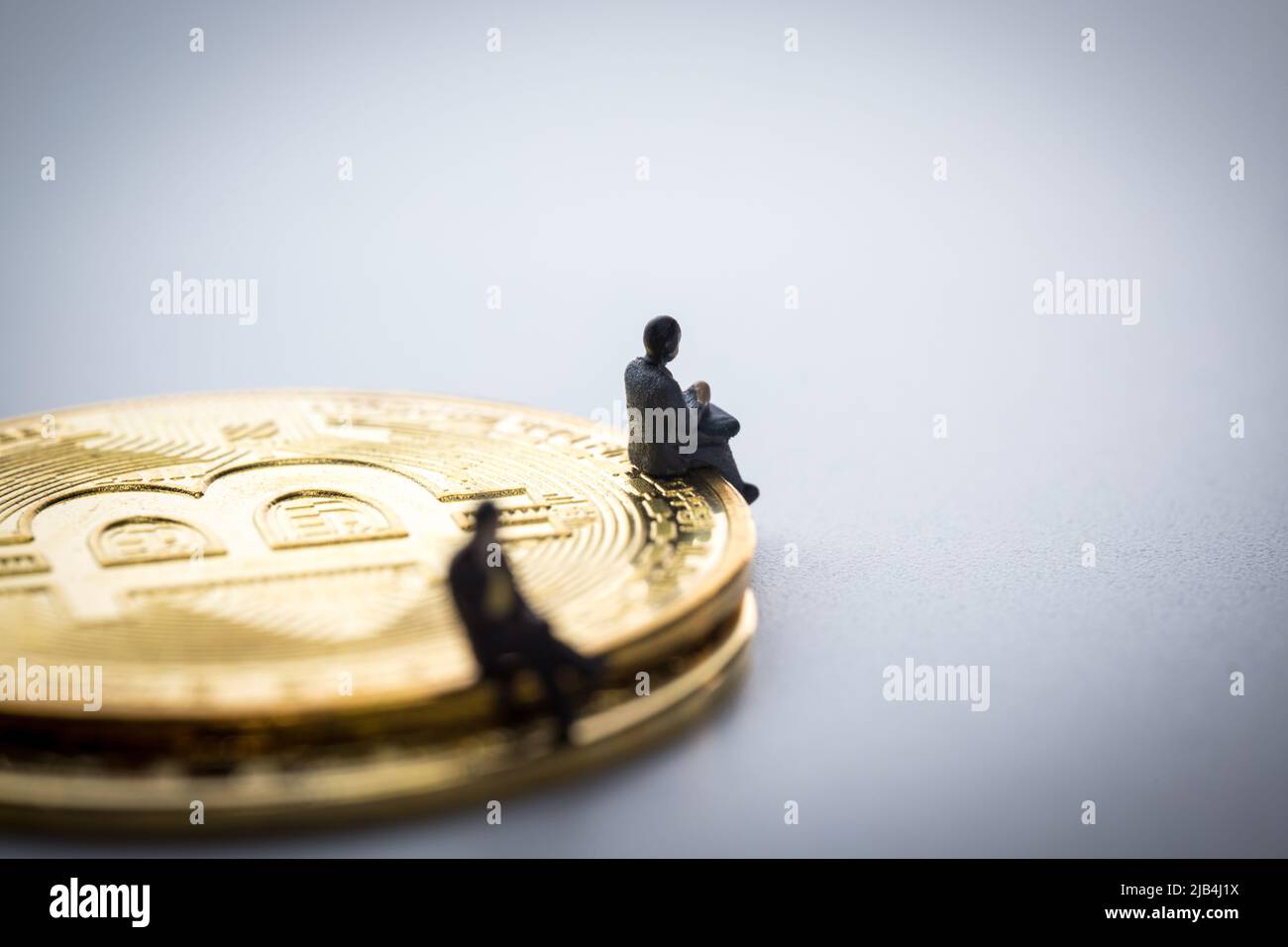 L'homme d'affaires miniature assis sur les bitcoins sur fond blanc Banque D'Images