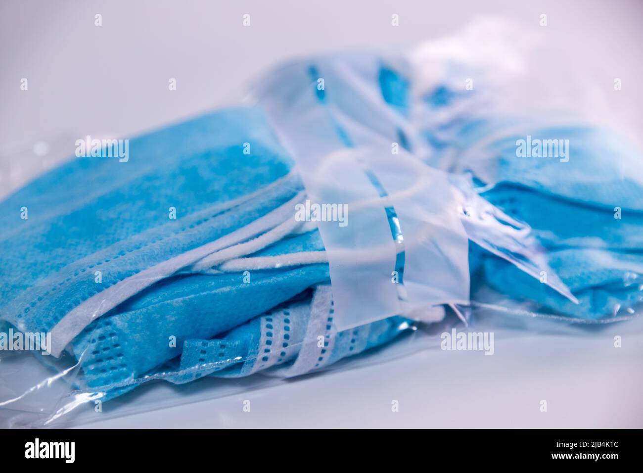 Masques faciaux bleus froissés déjà utilisés emballés dans un sac à fermeture éclair transparent sur fond blanc. Banque D'Images