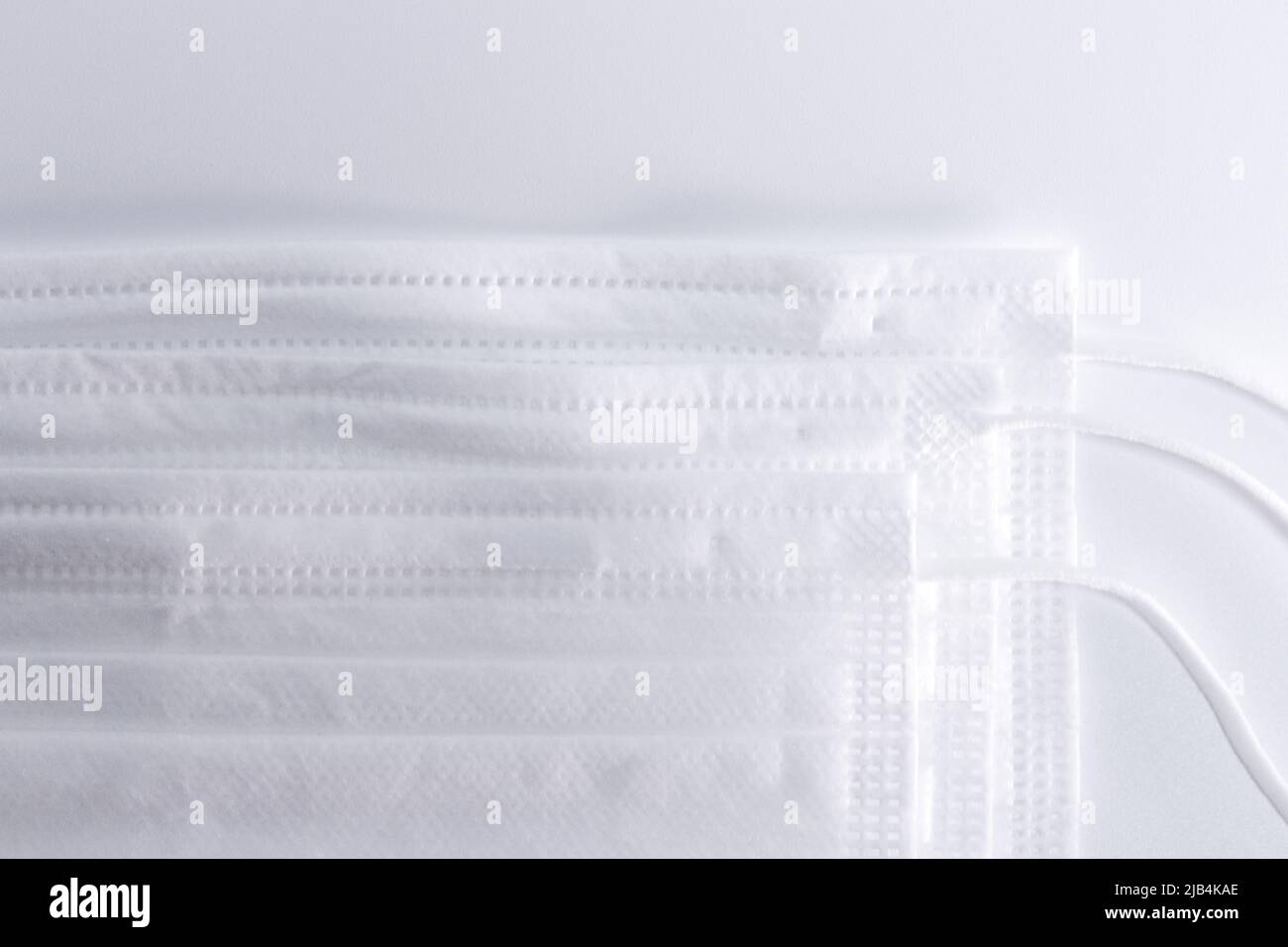 Pile de masques blancs (couvre-visage) sur fond blanc. Banque D'Images