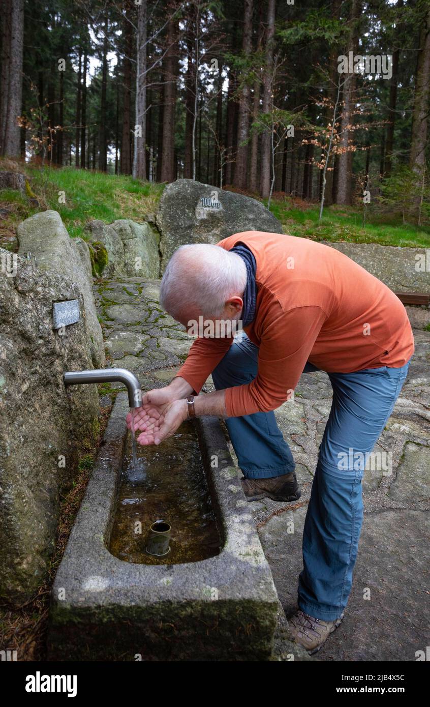 Le randonneur se rafraîchit à la fontaine d'eau de source à la place de 1000 m, Sternstein circulaire Trail, Bad Leonfelden, région de Muehlviertel, Upper Banque D'Images