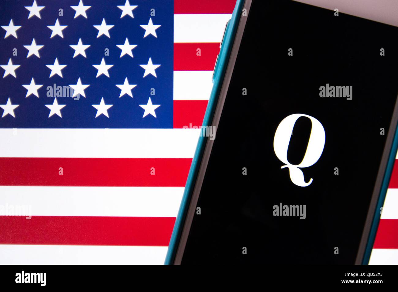 Kumamoto / JAPON - Oct 20 2020 : le logo de Qanon, un groupe de conspiration d'extrême droite, sur iPhone avec arrière-plan drapeau américain Banque D'Images
