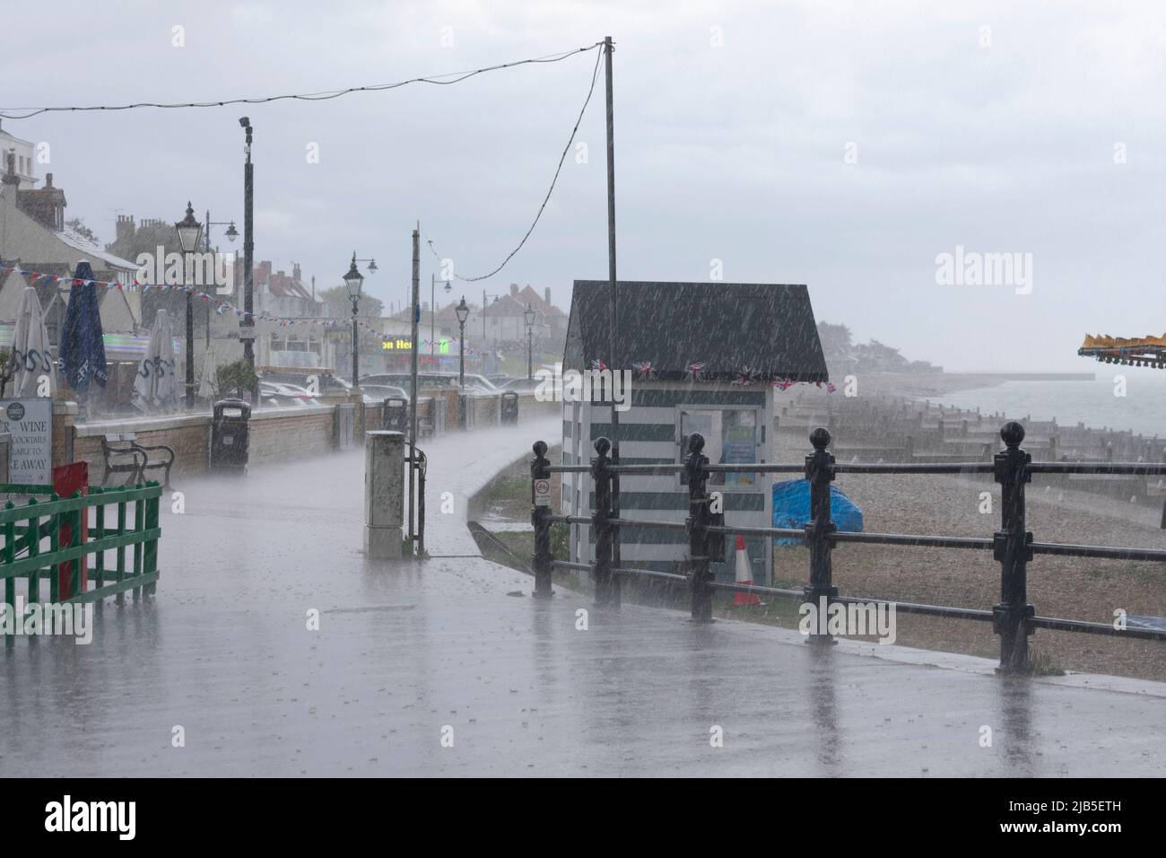 Une descente gâte l'après-midi à la baie de Herne avec la pluie qui descend sur la promenade, forçant les gens à s'abriter. Banque D'Images