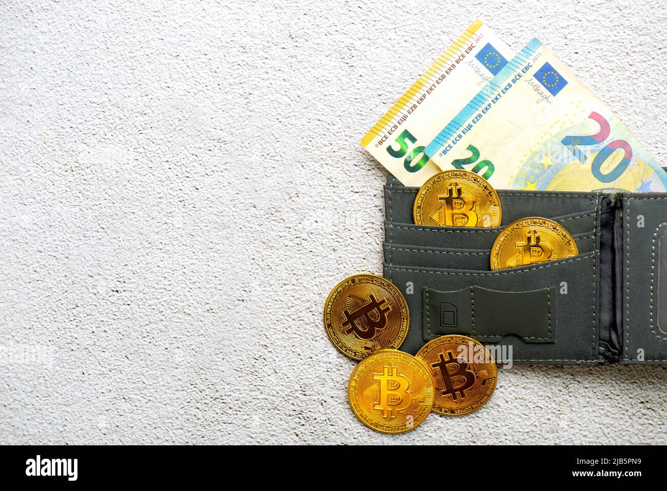 Vue de dessus des pièces de monnaie en bitcoin dorées dans un portefeuille avec des billets en euros sur le sol. Crypto-monnaie électronique Banque D'Images