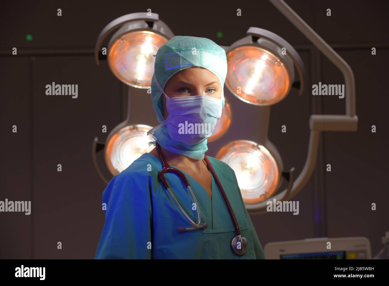 Une infirmière de théâtre d'anesthésie est vue dans un théâtre d'opération. Elle est vue vêtue de vêtements médicaux verts stériles avec un masque facial sur son visage. Banque D'Images