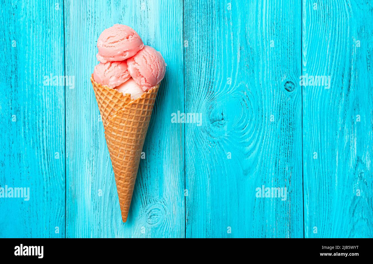 Crème glacée à la framboise dans un cornet de gaufres sur fond bleu. Banque D'Images