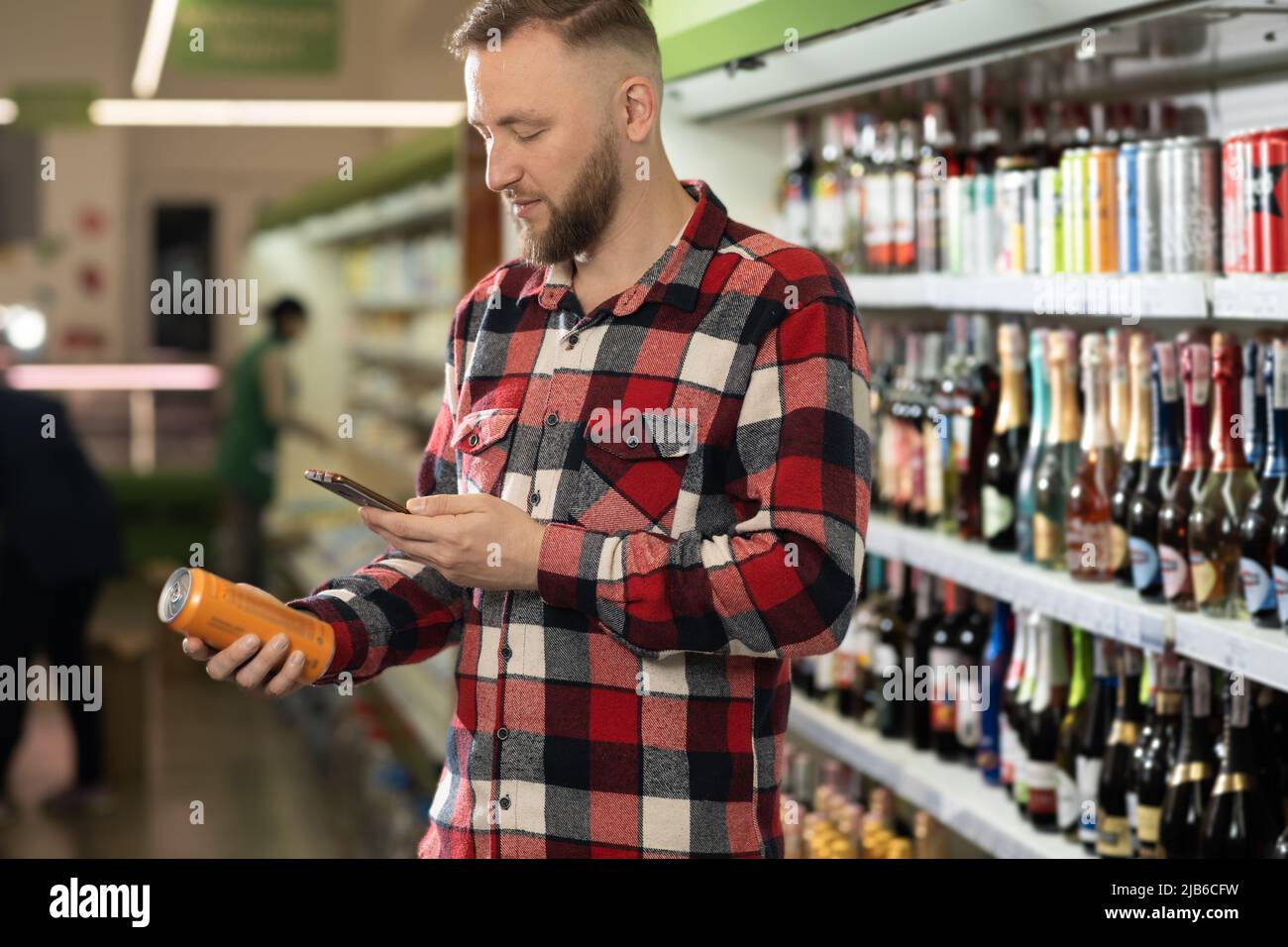 shopping dans le département du vin du supermarché, beau homme choisissant la bière dans la canette, barbu homme debout près des étagères avec de l'alcool, acheter de l'alcool Banque D'Images