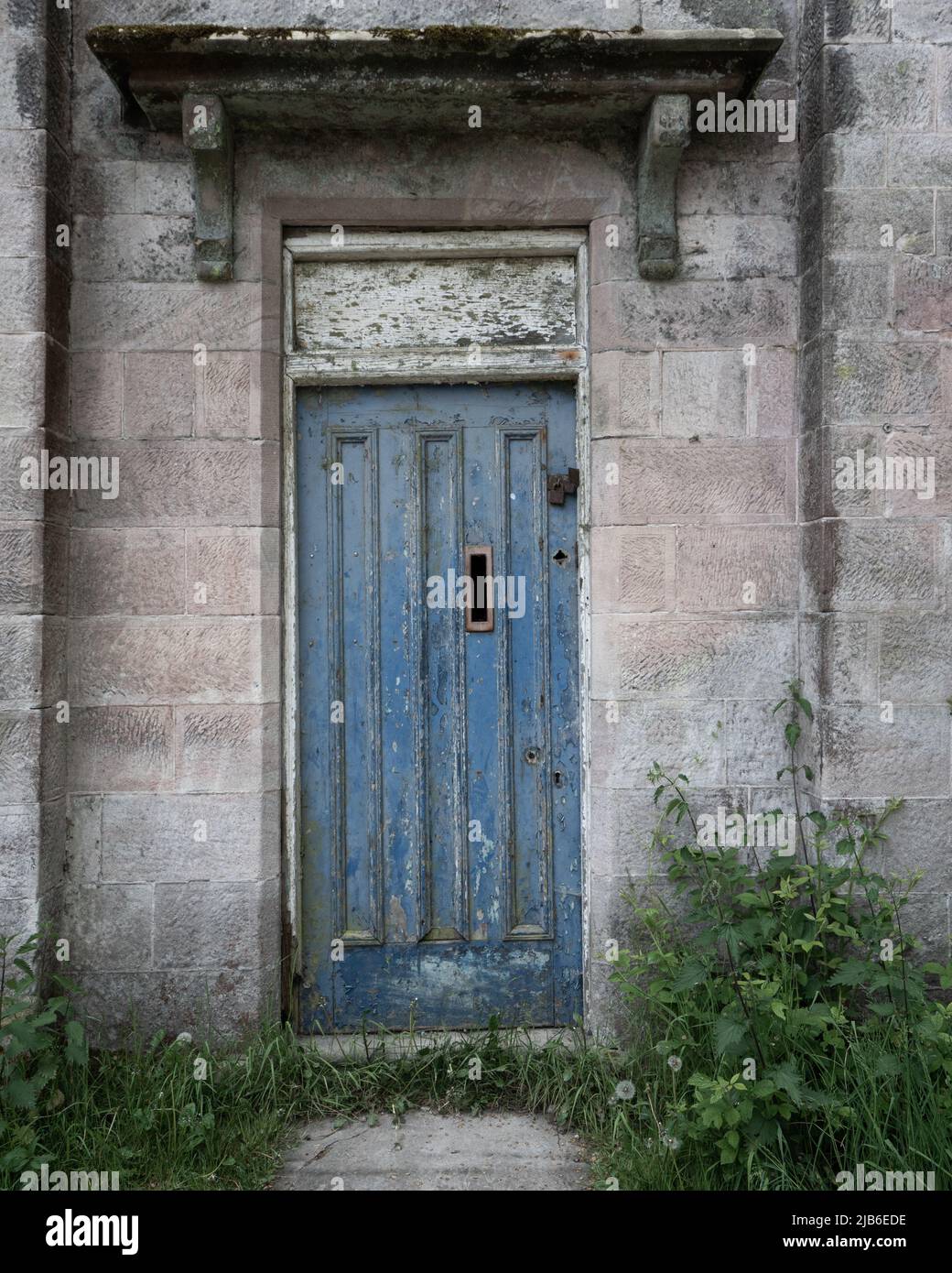 Porte bleue altérée avec peinture écaillée dans l'entrée du bâtiment historique en pierre Banque D'Images