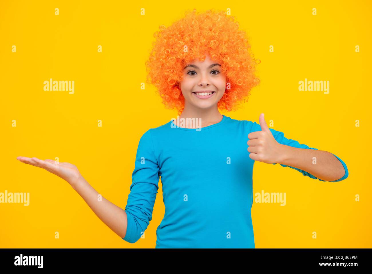 Belle adolescente dans perruque isolée sur jaune. Perruque clown amusante. Joyeux portrait d'adolescent. Fille souriante. Banque D'Images