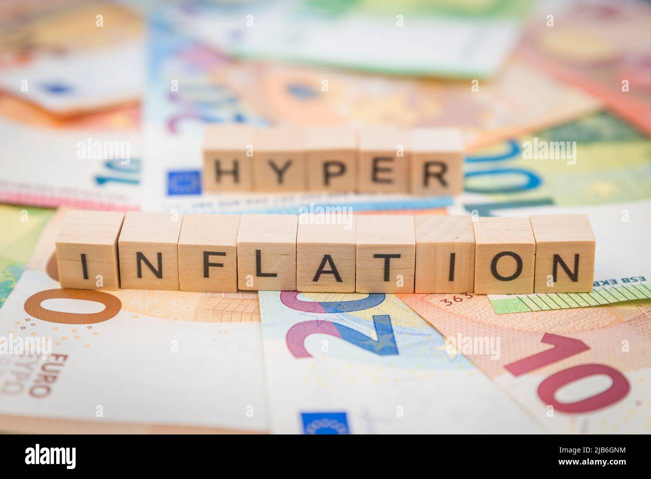 Le mot inflation et hyper en arrière-plan sur les billets de banque des billets en euros écrits avec des cubes en bois Banque D'Images