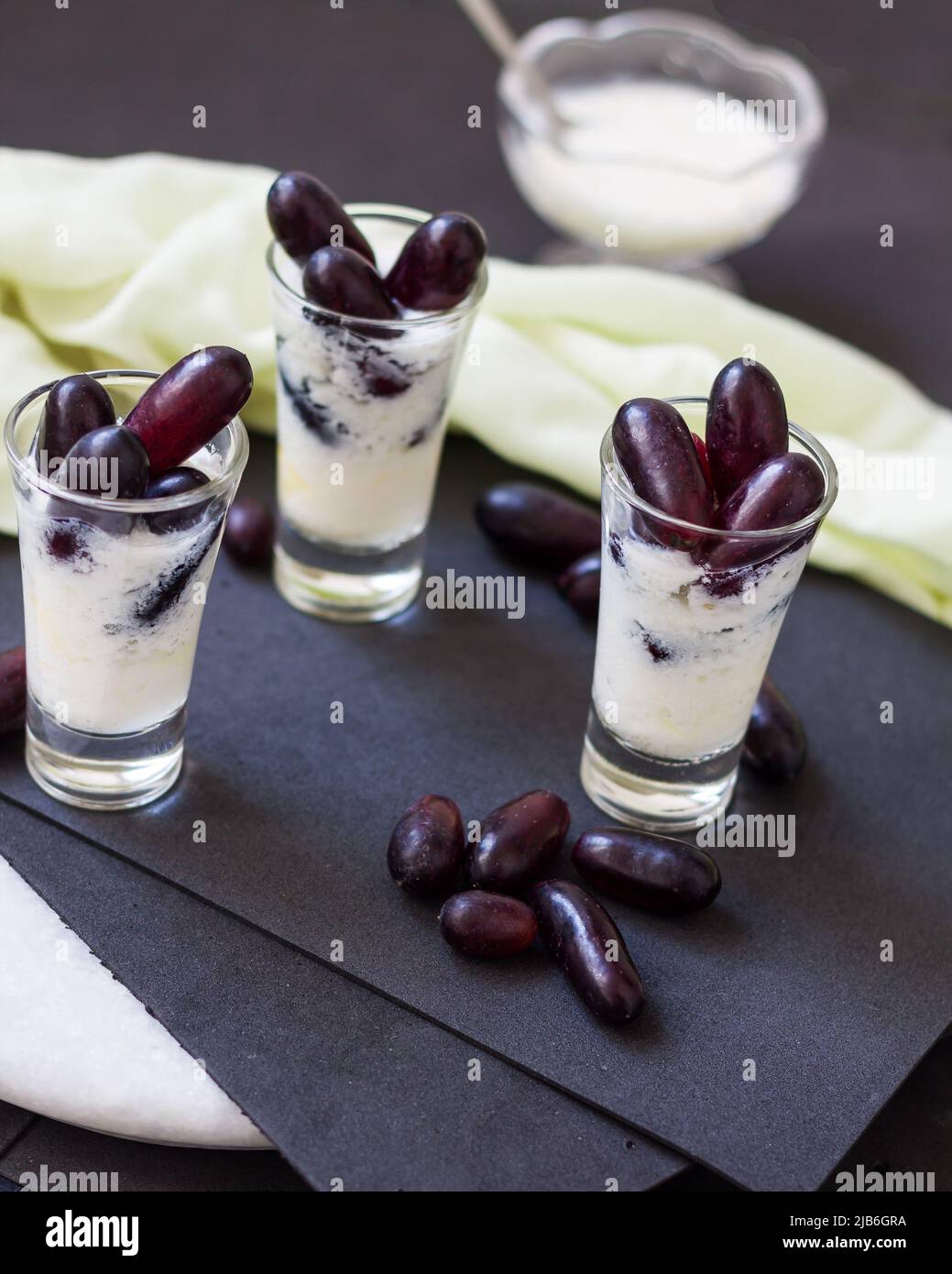 Boisson d'été Lassi, saine, douce, fraîche boisson biologique à base de yaourt glacé, dahi ou caillé et raisins rouges.smoothie aux fruits indiens sur fond noir. Banque D'Images