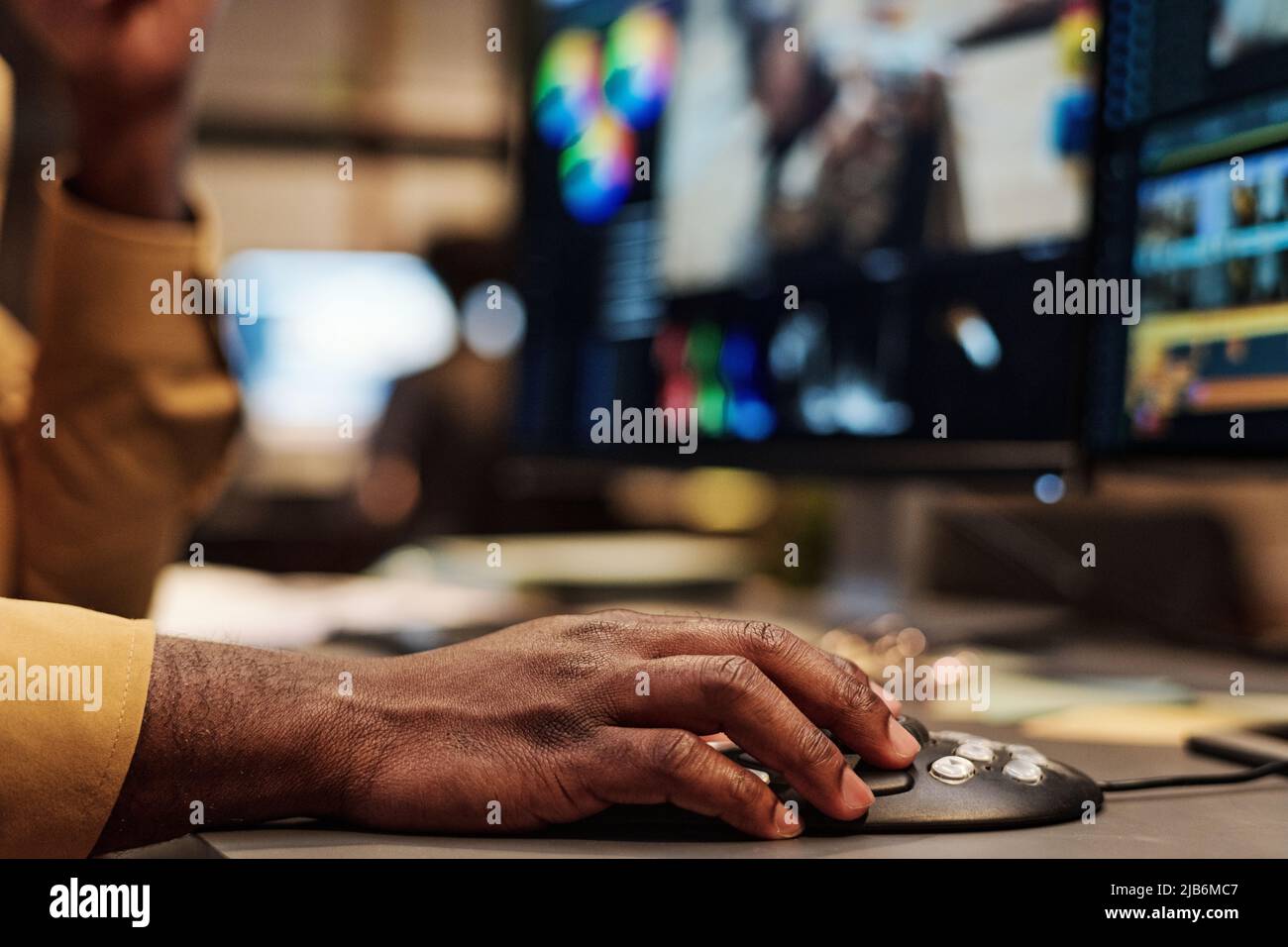 Gros plan d'un coloriste africain utilisant une souris d'ordinateur pour retoucher des photos sur un ordinateur sur son lieu de travail Banque D'Images