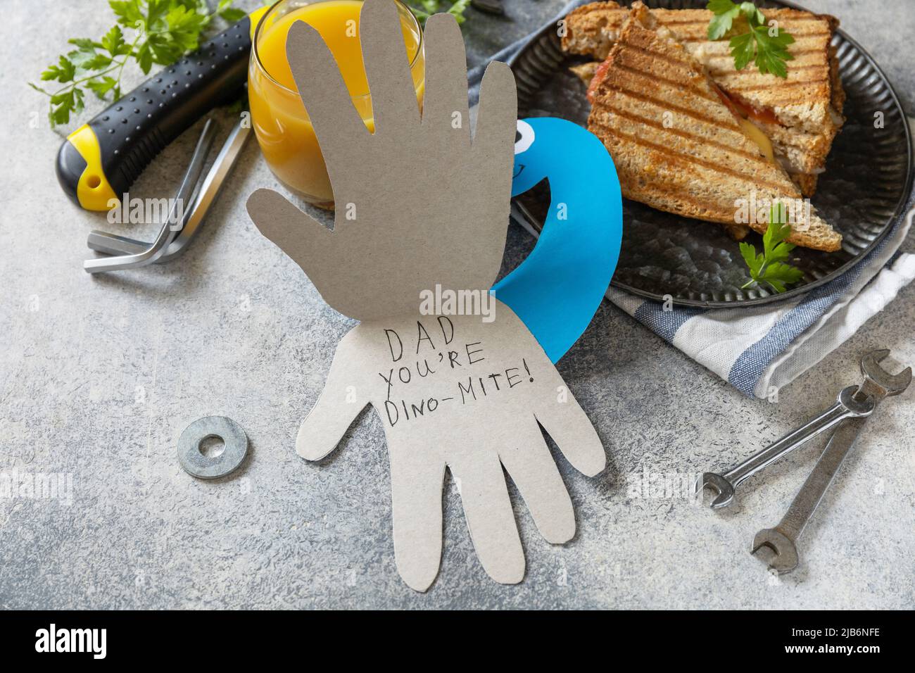 Bonne fête des pères. Carte de fête des pères dinosaure et petit déjeuner à la maison pour papa sur table en pierre grise. Banque D'Images