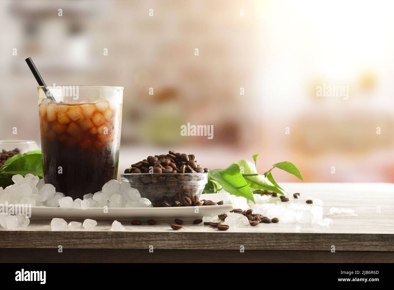 Présentation de café glacé sur un banc de cuisine avec des récipients pleins de grains de café et de glace pilée autour. Vue avant. Composition horizontale. Banque D'Images