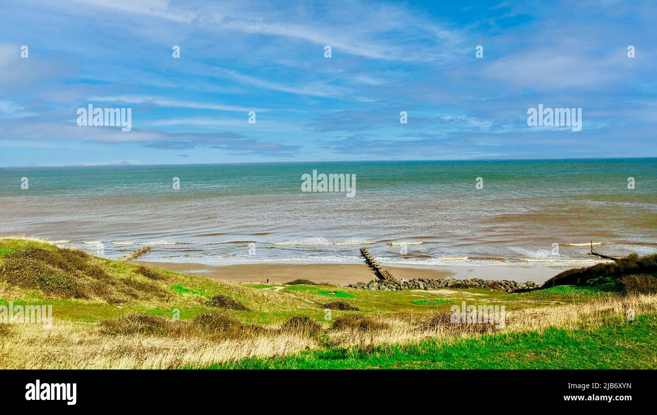 Vue sur la mer et la plage au large de la côte de Norfolk, près de Cromer, au Royaume-Uni. Une plage vide avec un brise-marée et de l'eau turquoise. Banque D'Images