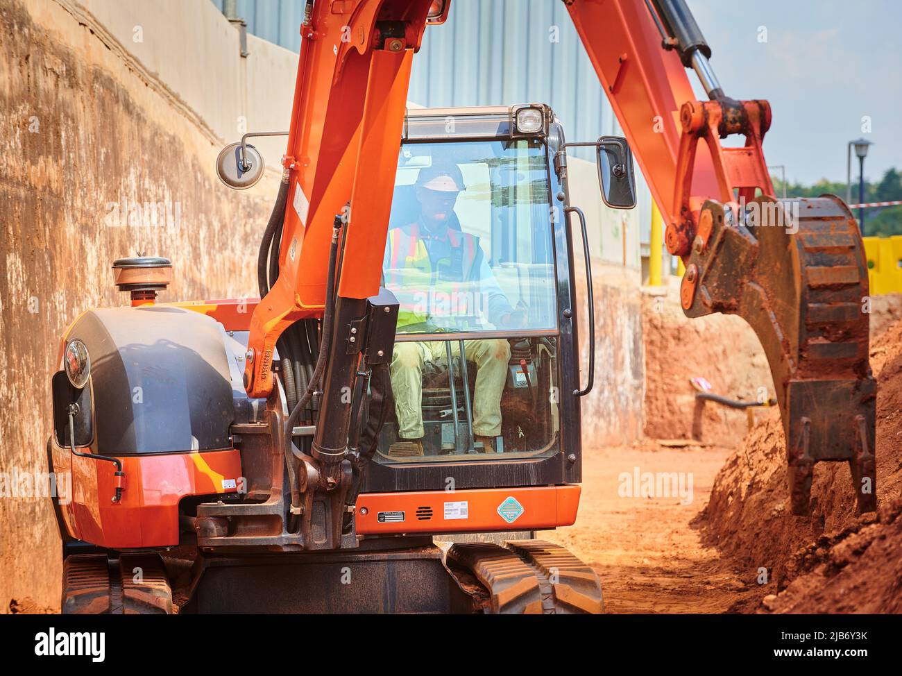 Pelle hydraulique creusant une tranchée pour retenir la paroi et la route. Travaux d'excavation sur site. Banque D'Images