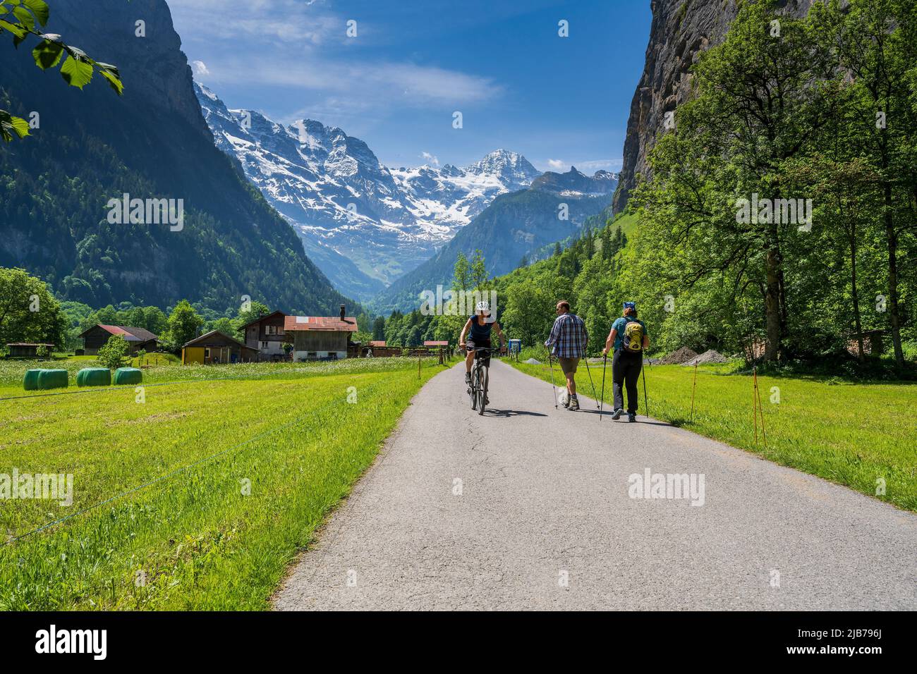 Cycliste et randonneur sur un sentier pavé aux Alpes suisses enneigées en premier plan, Lauterbrunnen, canton de Berne, Suisse Banque D'Images