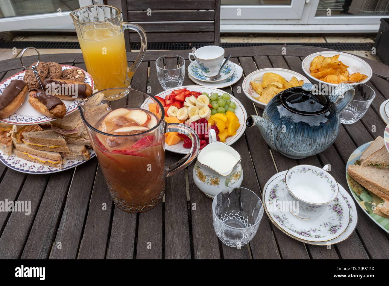 Le jour férié du Jubilé platine de la Reine - table pour un thé d'après-midi en famille dans le jardin avec sandwiches, gâteaux, thé, jus de fruits et fruits, juin 2022 Banque D'Images