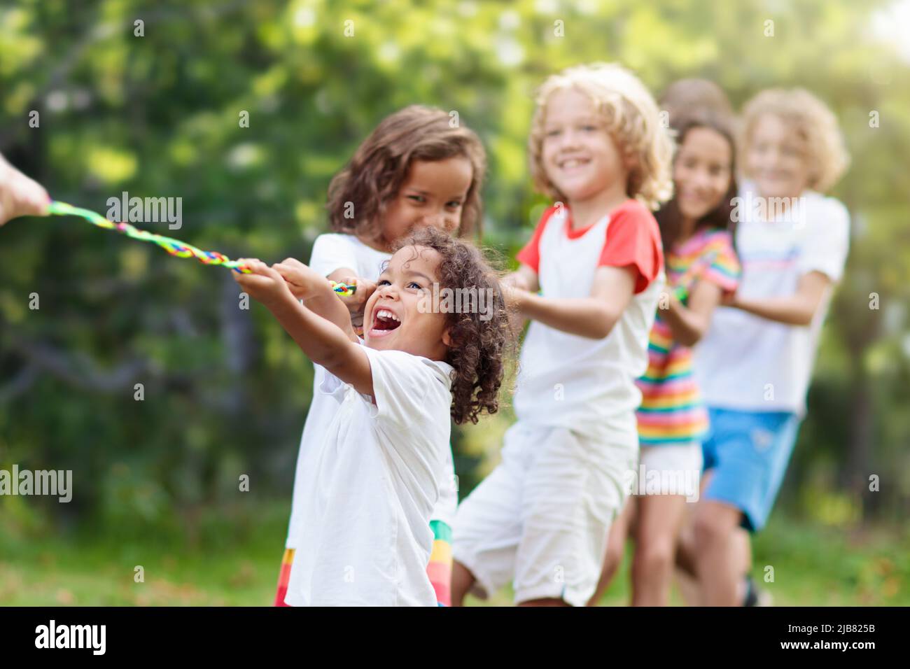 Les enfants jouent au remords de la guerre dans un parc ensoleillé. Activités d'été en plein air. Groupe d'enfants de race mixte tirer corde dans la journée de sport scolaire. Banque D'Images