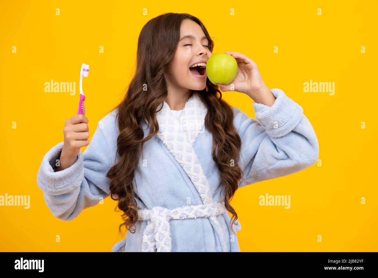 Vitamines de pomme pour des dents saines. Portrait de la jeune fille caucasienne tient une brosse à dents se brossant ses dents, routine du matin, hygiène dentaire, isolé dessus Banque D'Images
