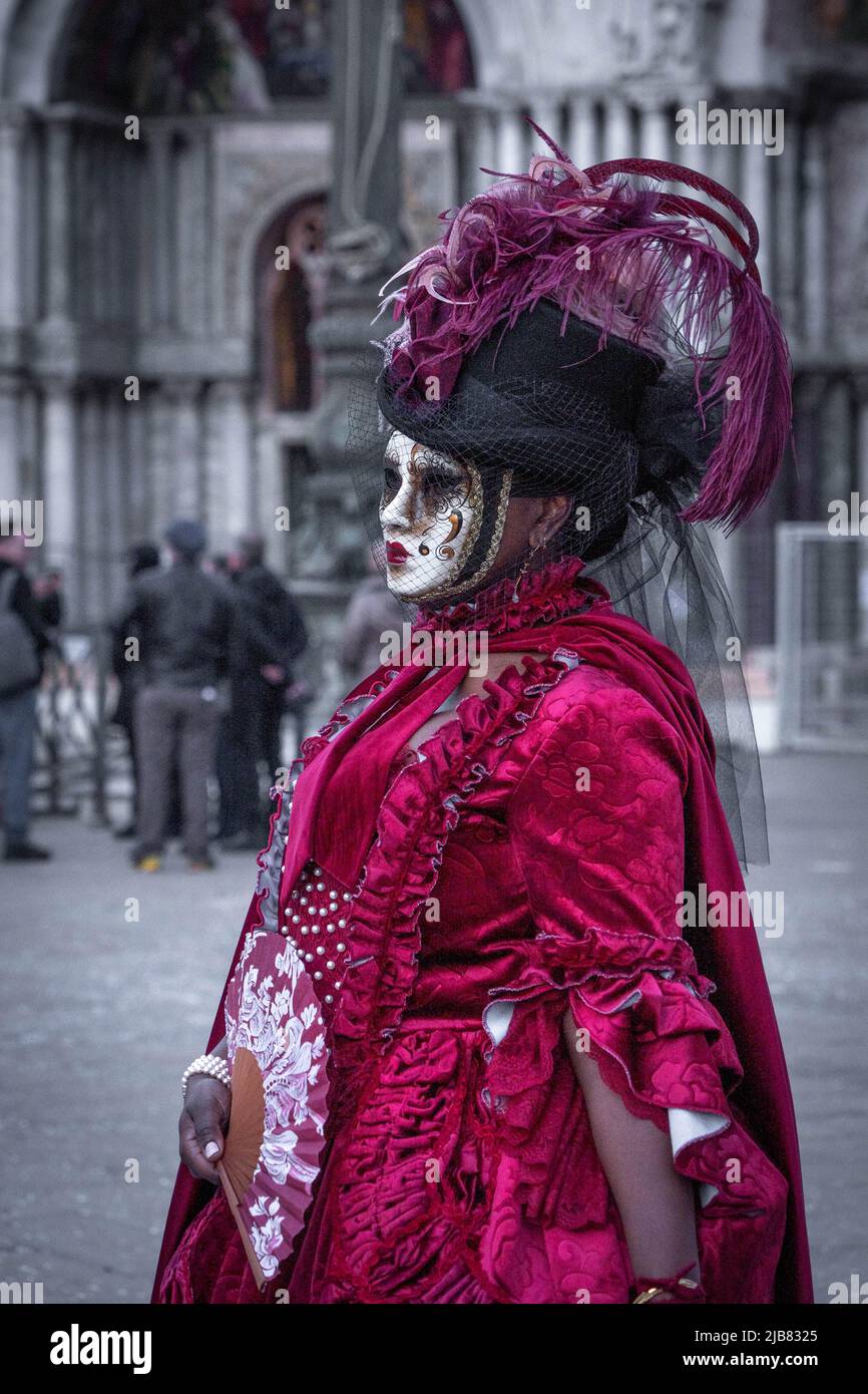 Venise, Italie - 18.02.2022: Femme masquée en robe rouge avec plumes  violettes sur chapeau noir au carnaval vénitien Photo Stock - Alamy