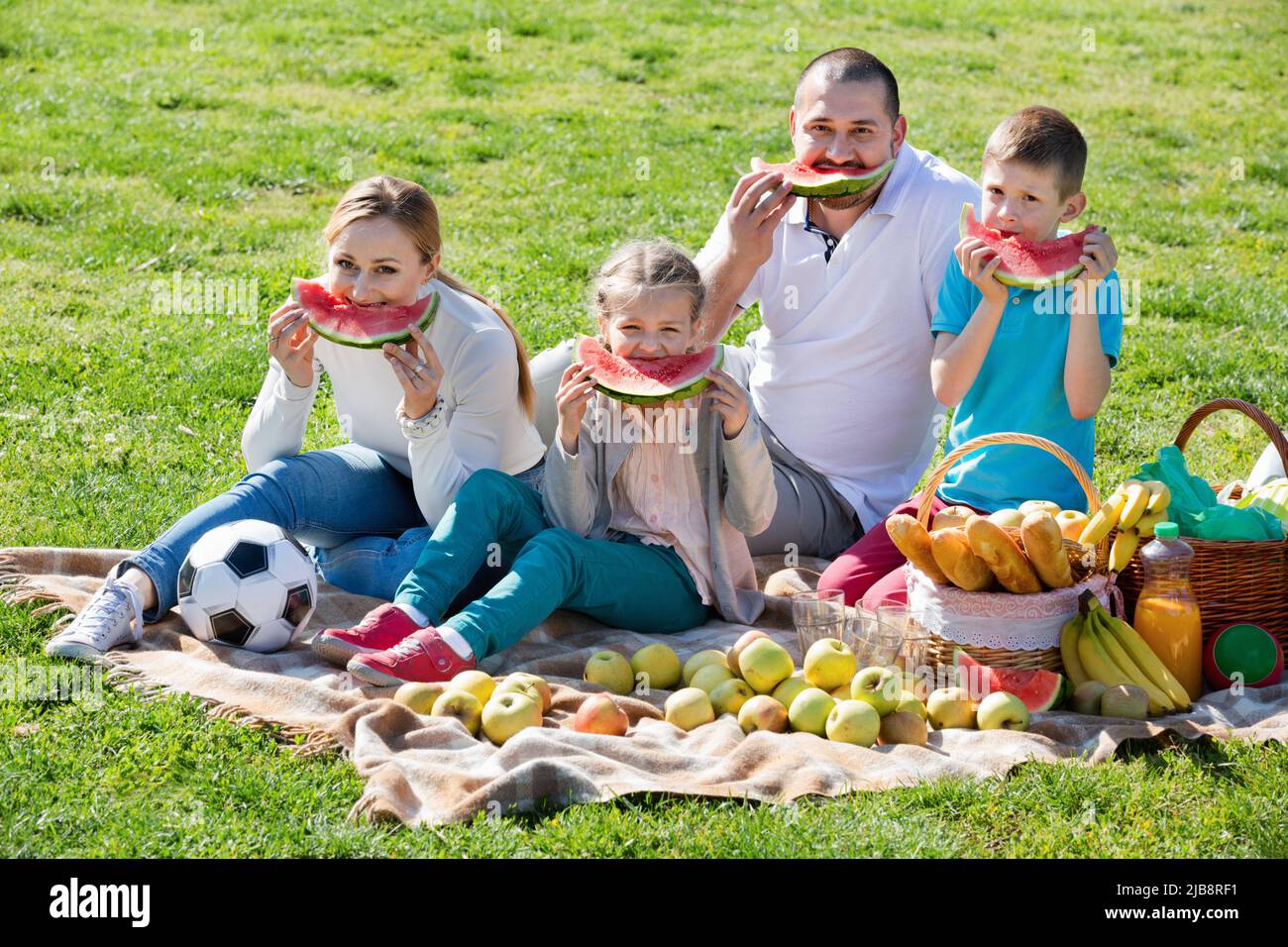 Famille souriante de quatre personnes ayant pique-nique et mangeant de la pastèque Banque D'Images