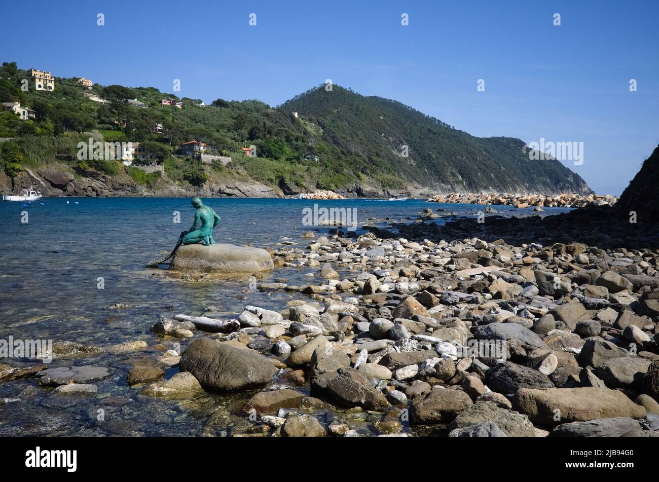 Monument en bronze au pêcheur avec filet de pêche dans ses mains assis sur la pierre sur le rivage de la baie de Baia del Silenzio en mer Ligurienne, Sestri Levante, Italie. Banque D'Images